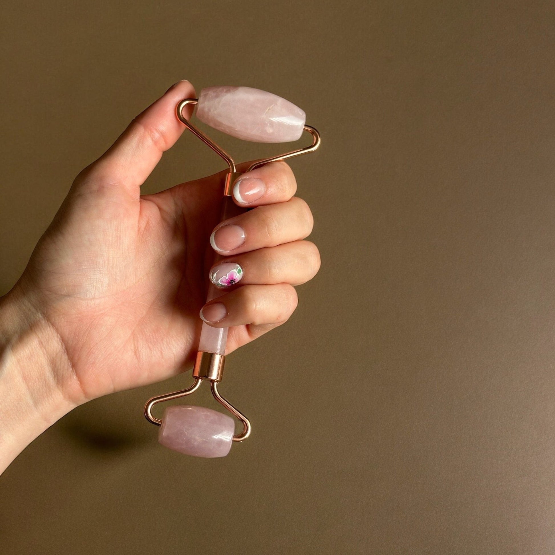 Rose quartz face roller on a hand