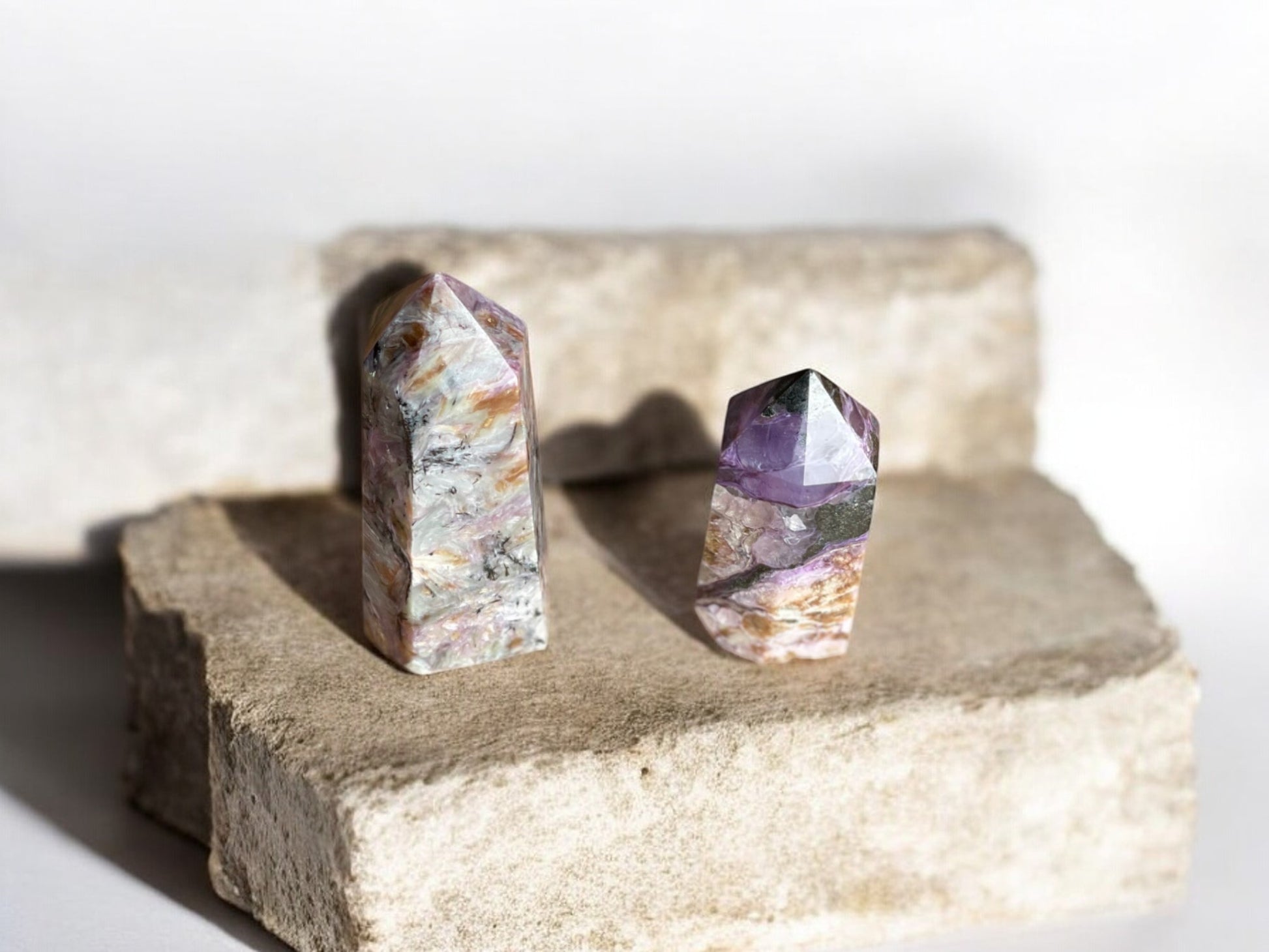 Two charoite crystal towers on concrete slab