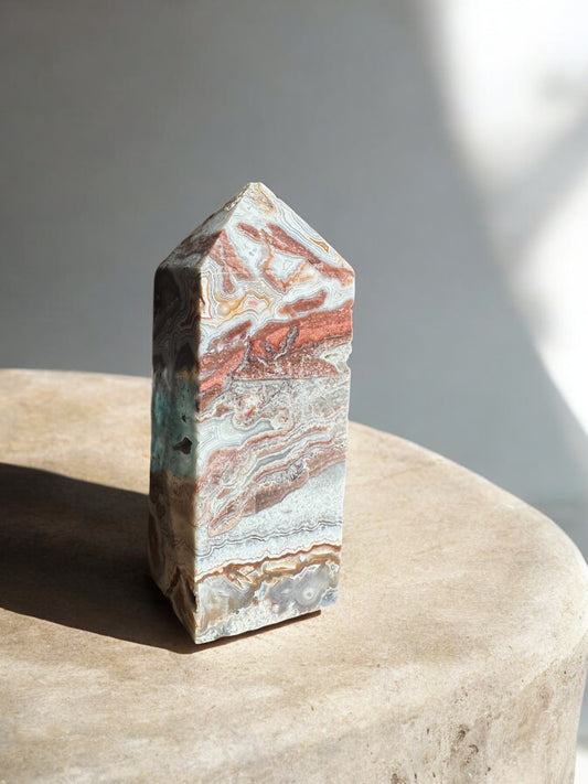 Crazy lace agate crystal obelisk on a concrete slab